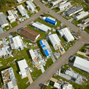 Aerial view of storm-damaged homes, some with blue roof tarps