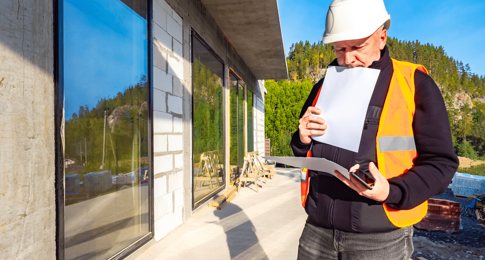 Builder reviewing paperwork on home jobsite