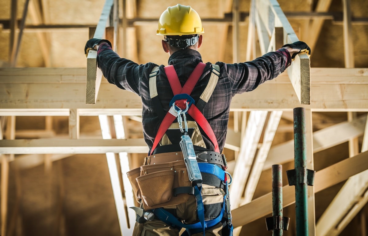 Construction worker standing amid roof trusses in house