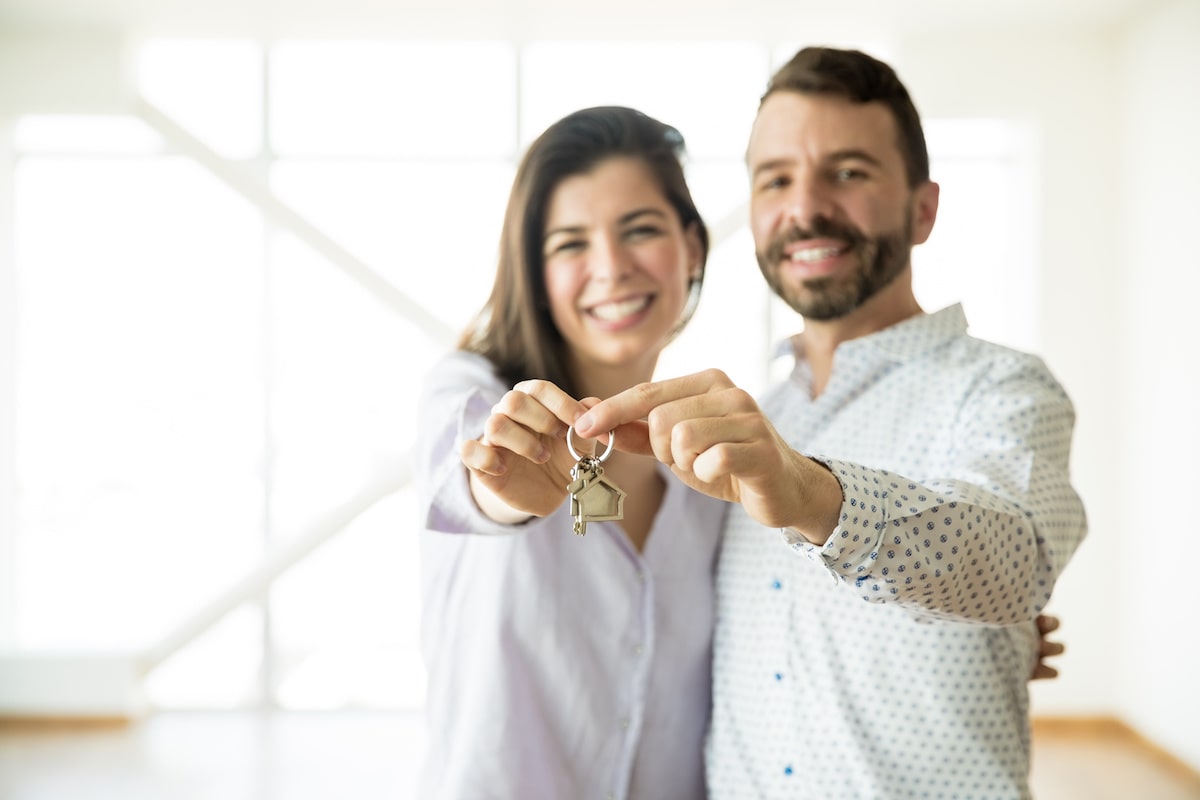 A man and woman hold up a set of keys.