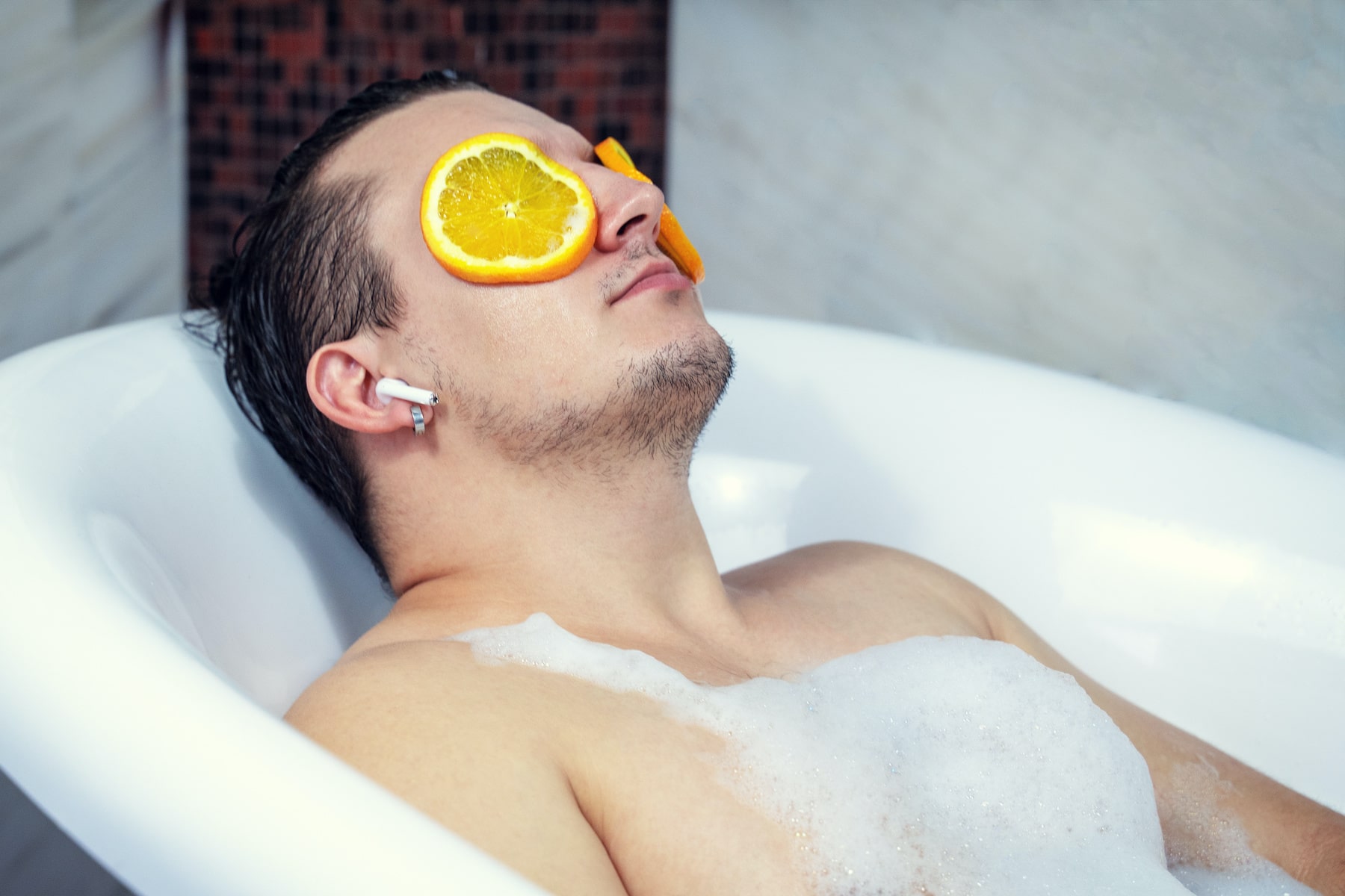 Man in sap bath tub with orange slices on his eyes