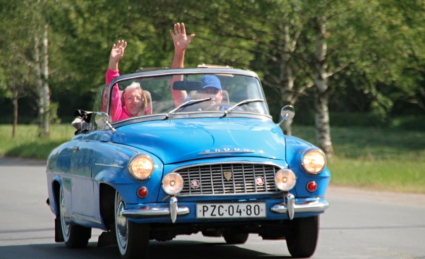 Couple in car driving away and waving good-bye