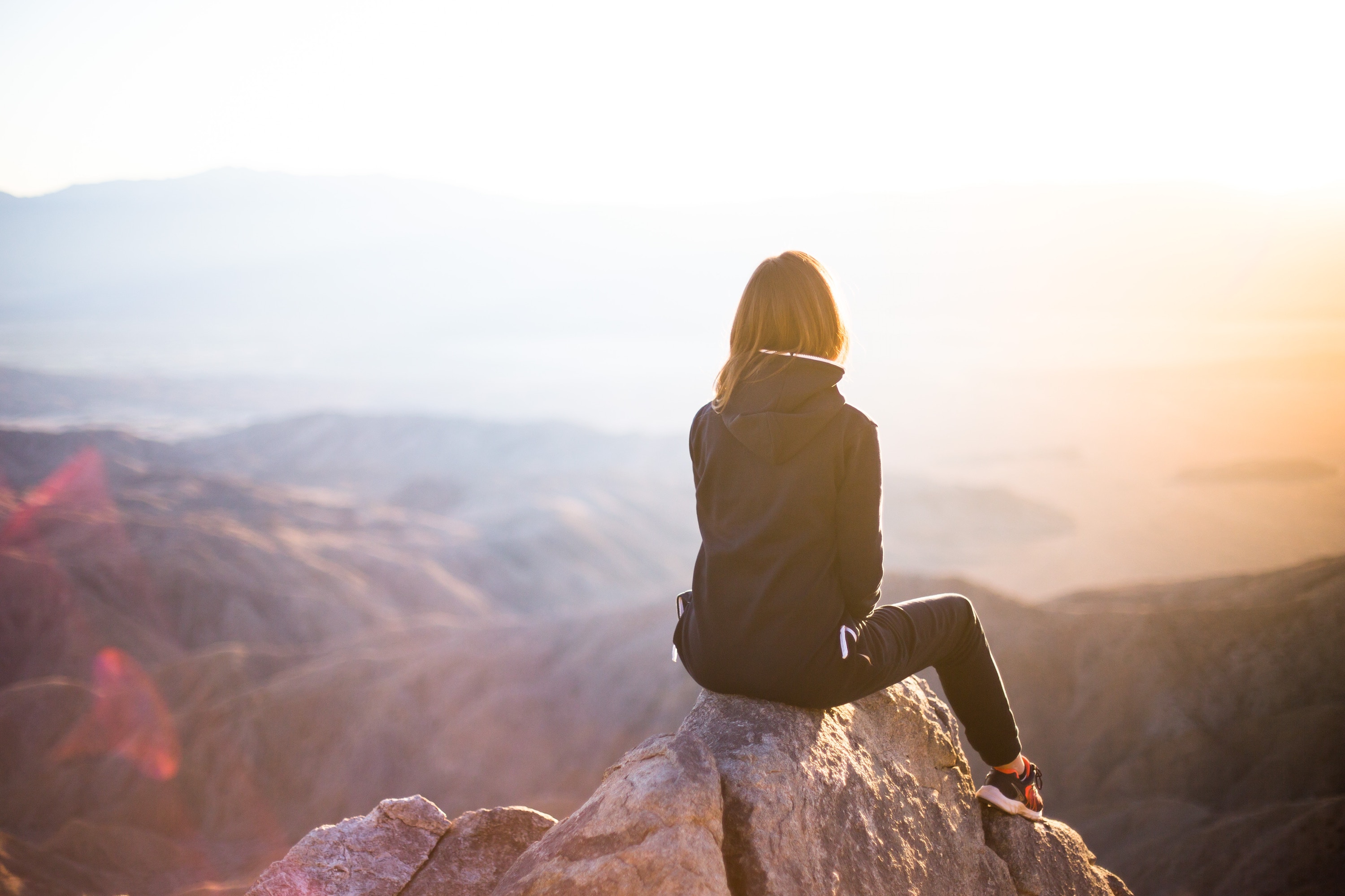 Woman sitting on a peak in mountains