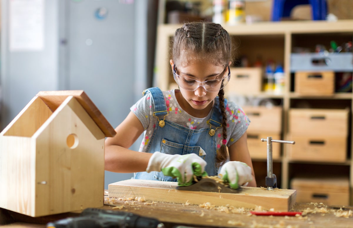 Young girl building birdhouse