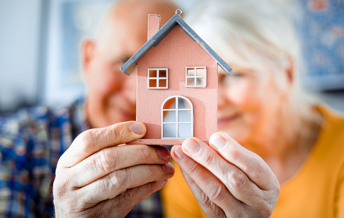 Old couple holding small house model