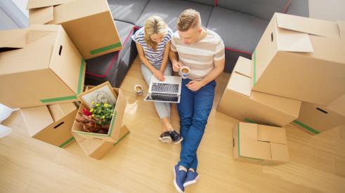 Young couple sitting on floor around moving boxes