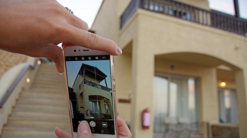 Woman taking a photo of house with cell phone