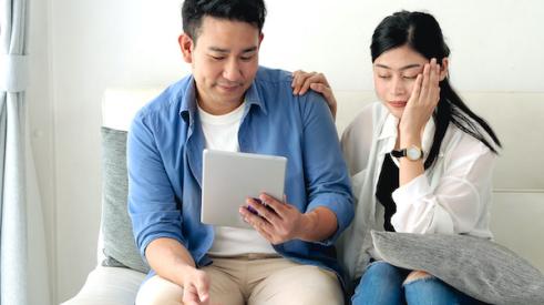 Couple looking upset as they realize they can't afford to buy a home