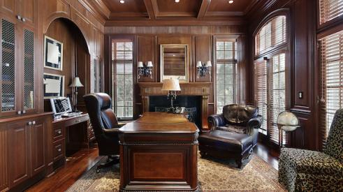 Wood-paneled home office with leather chairs and heavy wood desk