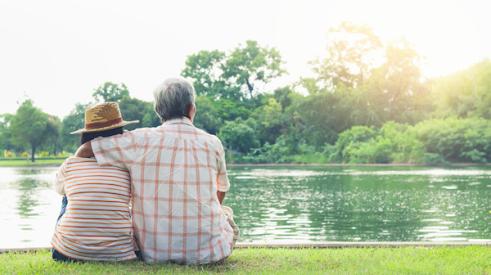 An older couple sitting by a lake