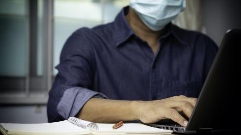 Man working at laptop with mask