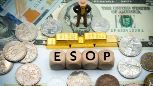 Business leader figurine standing on money in front of gold bars and letters spelling 'ESOP'