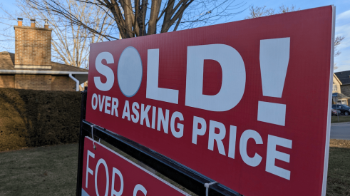 In a hot housing market, this red and white sign says home sold above asking price