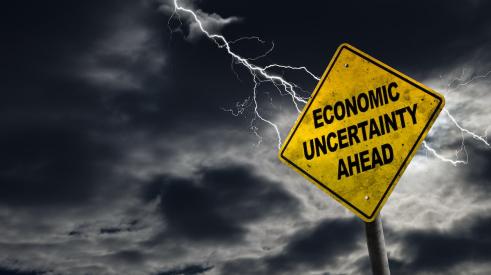 A yellow sign says 'Economic Uncertainty Ahead'