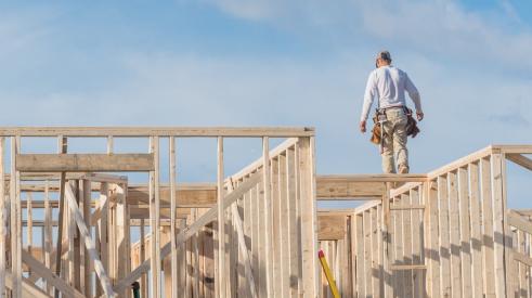 Builder walking on house frame