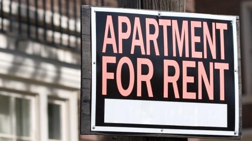 Orange and black 'apartment for rent' sign on light pole