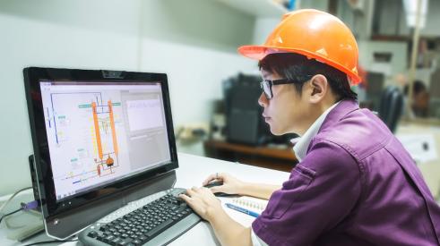 Construction student with hard hat working on computer