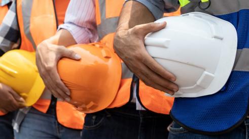 Construction workers standing in line holding hard hats