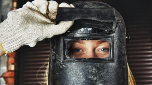 Young woman with blonde hair wearing welder mask