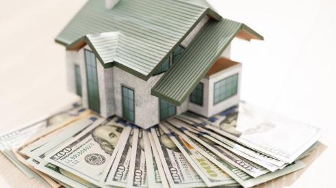 Small house model on stack of cash