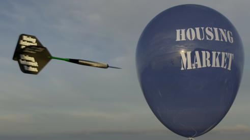 Dart labeled 'rising interest rates' flying toward blue housing market balloon 