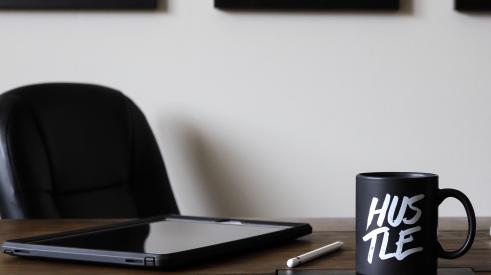 'Hustle' mug on desk with tablet