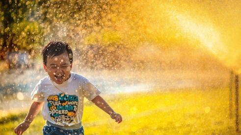 Boy running through sprinkler