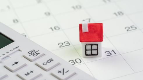 Small house and calculator on monthly calendar