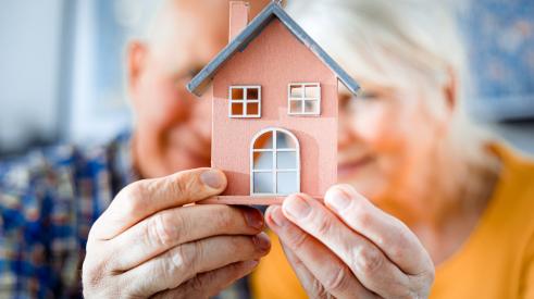 Old couple holding small house model