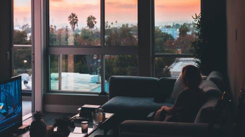 Woman sitting in living room during sunset