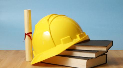 Construction hard hat, books, and diploma on desk