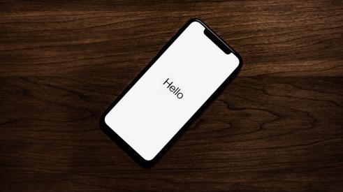 iPhone on table screen reads 'Hello'