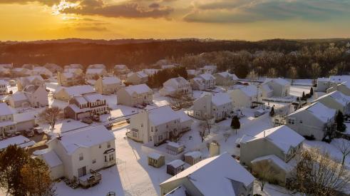 Aerial view of sun rising above snowy neighborhood