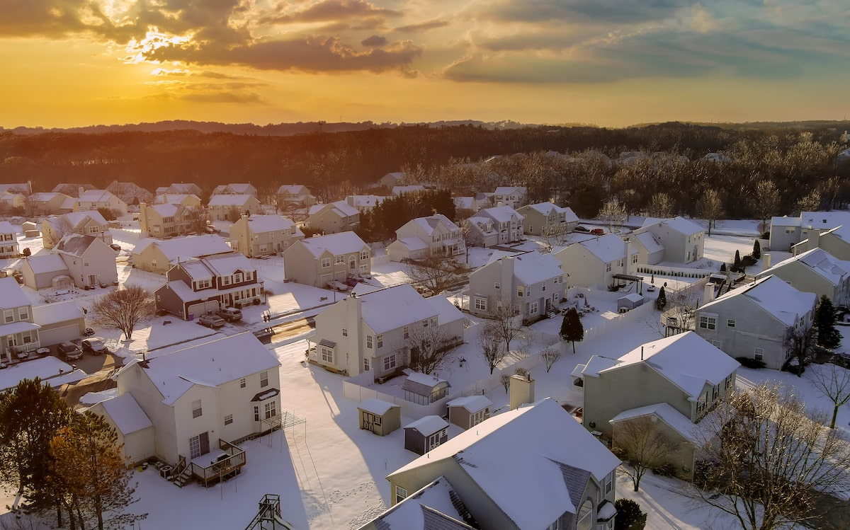 Aerial view of sun rising above snowy neighborhood