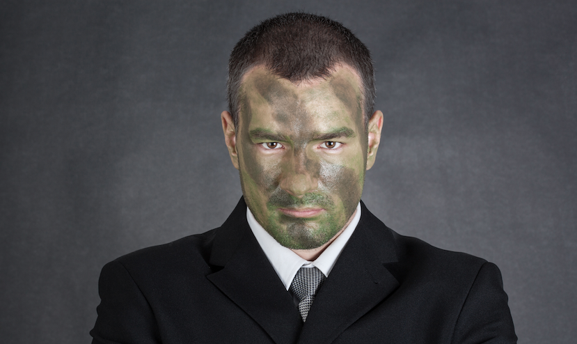 businessman wearing suit with face painted in camo for surviving battle