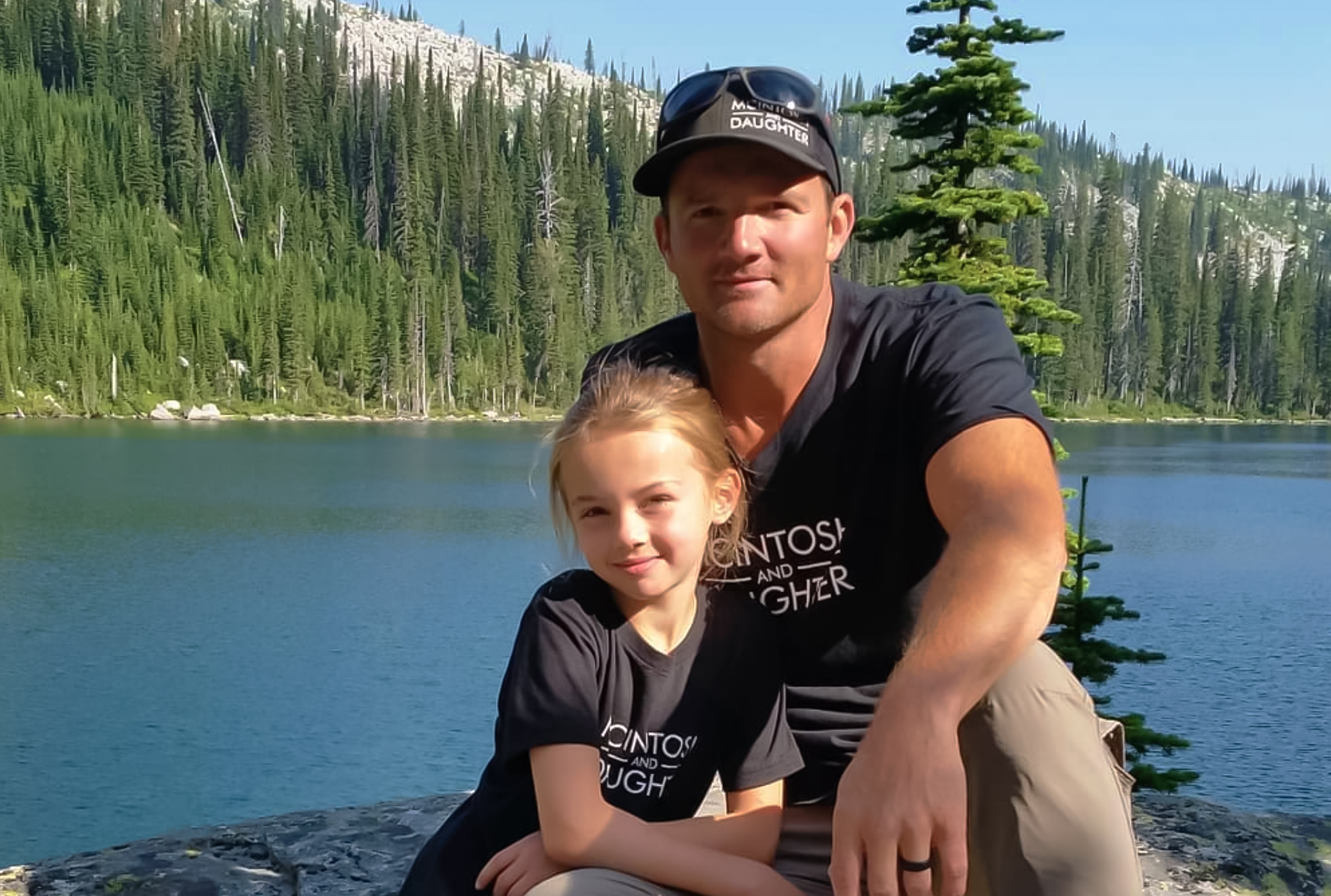 Man and daughter wearing matching shirts by a lake