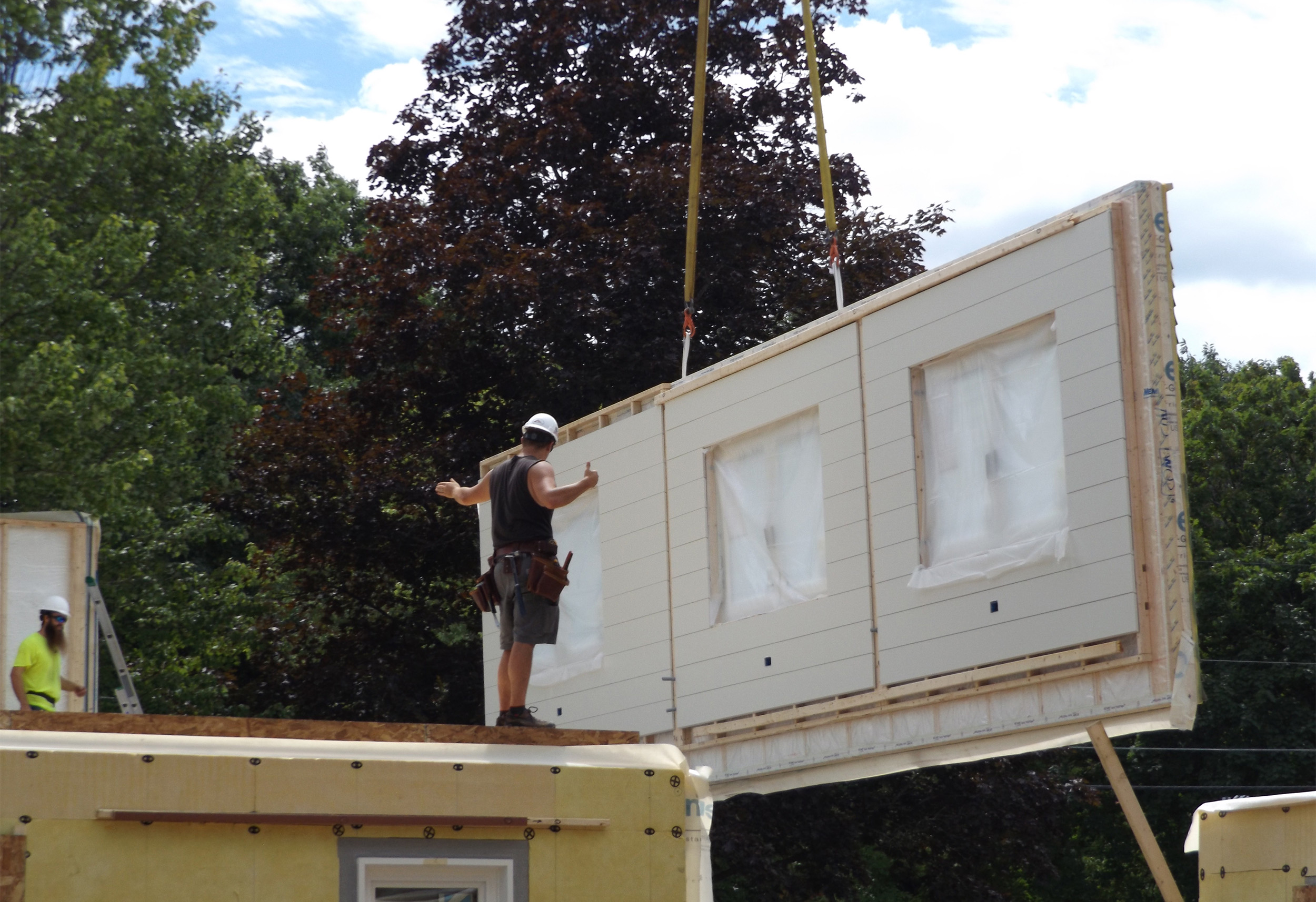 Construction worker installing prefabricated wall panel on jobsite