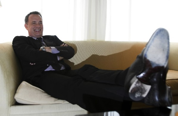Actor Tom Hanks sitting on a sofa with his feet up, relaxing