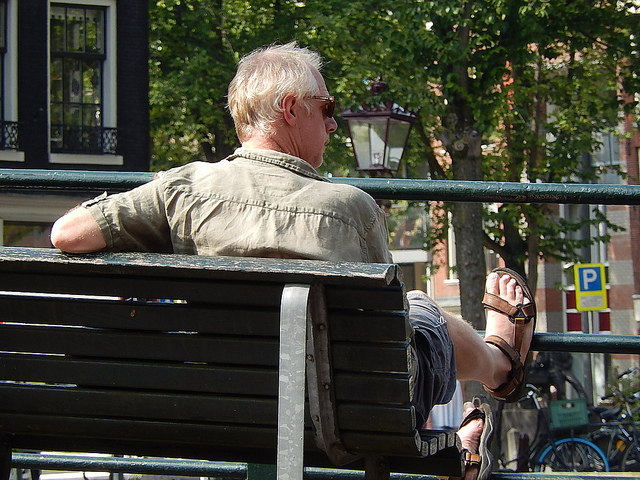 Baby Boomer man sitting on park bench in sun