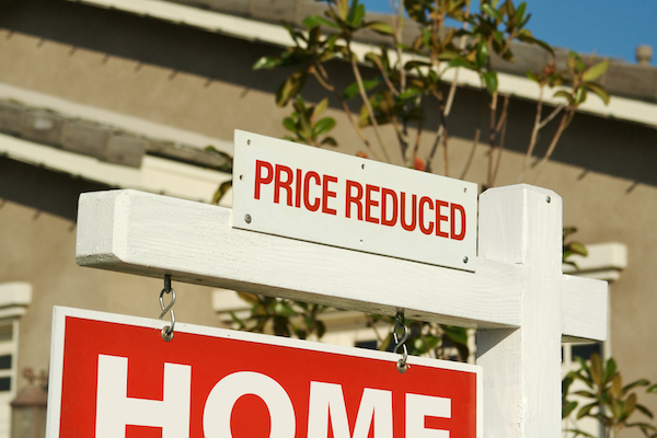 Home for sale sign with 'price reduced' sign at top