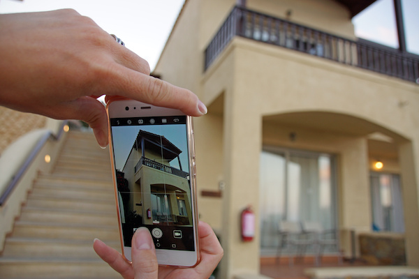 Woman taking a photo of house with cell phone