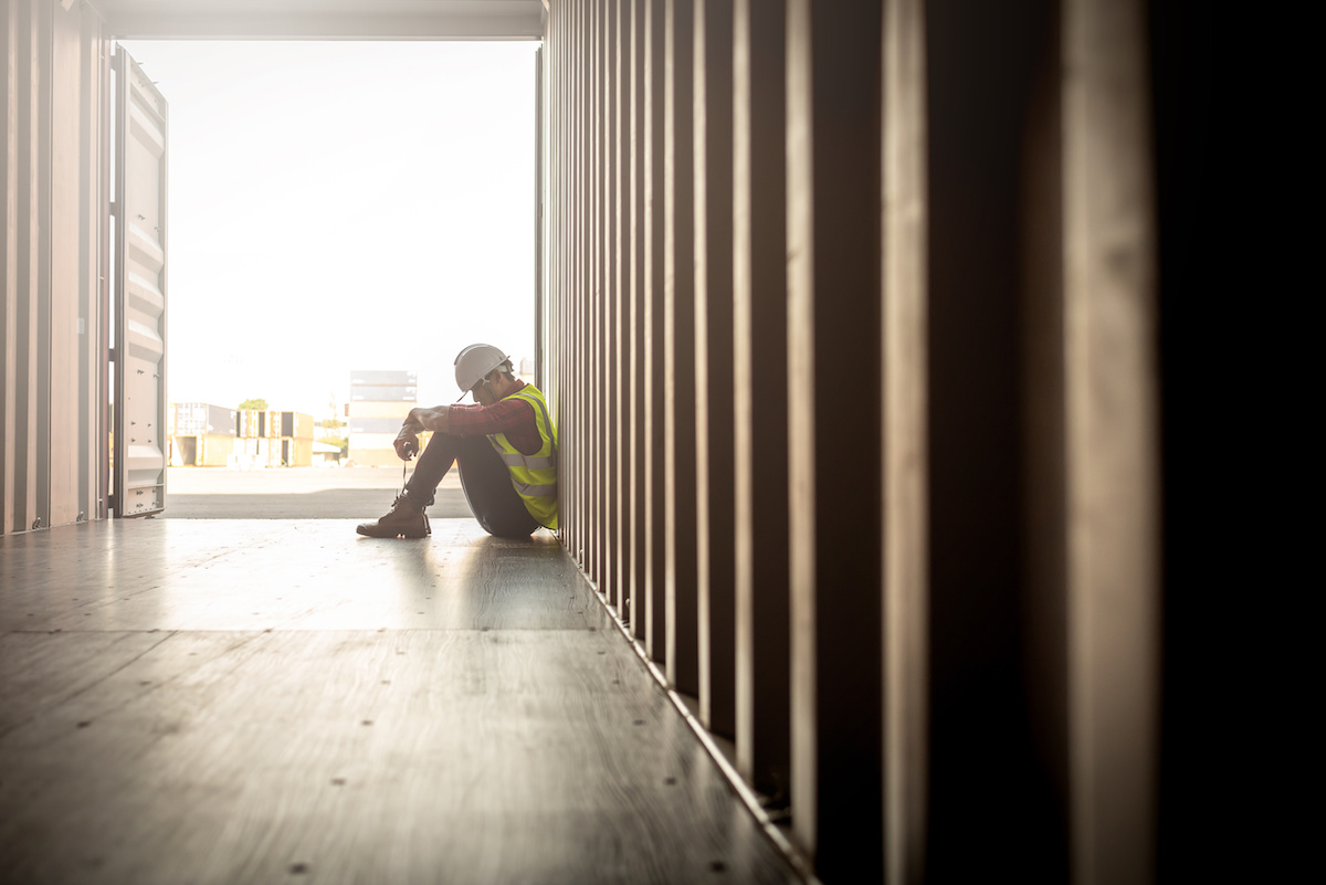 Construction worker sitting with head down