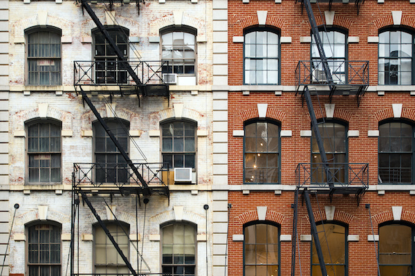 Exterior of two brick New York City apartment buildings with fire escapes