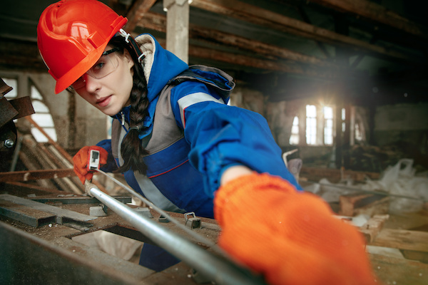 Woman measuring pieces of lumber on a construction site