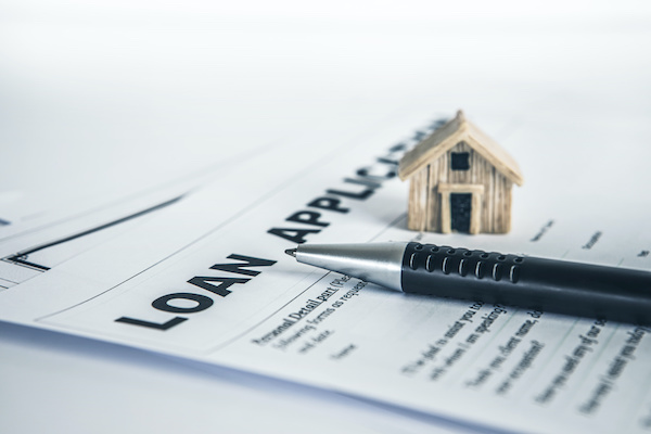 Loan application with home figurine and pen