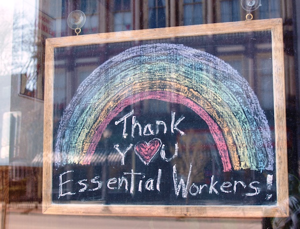A chalkboard sign saying 'Thank you essential workers' hanging in a window