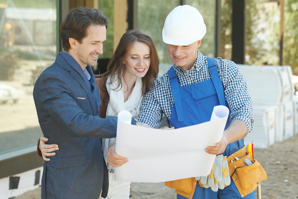 Builder smiling and showing plans to smiling clients