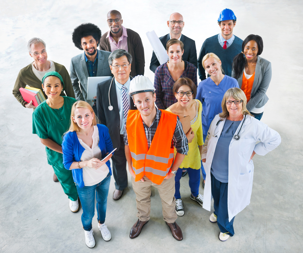 A group of people in different lines of work stand in a circle, looking up at the camera.
