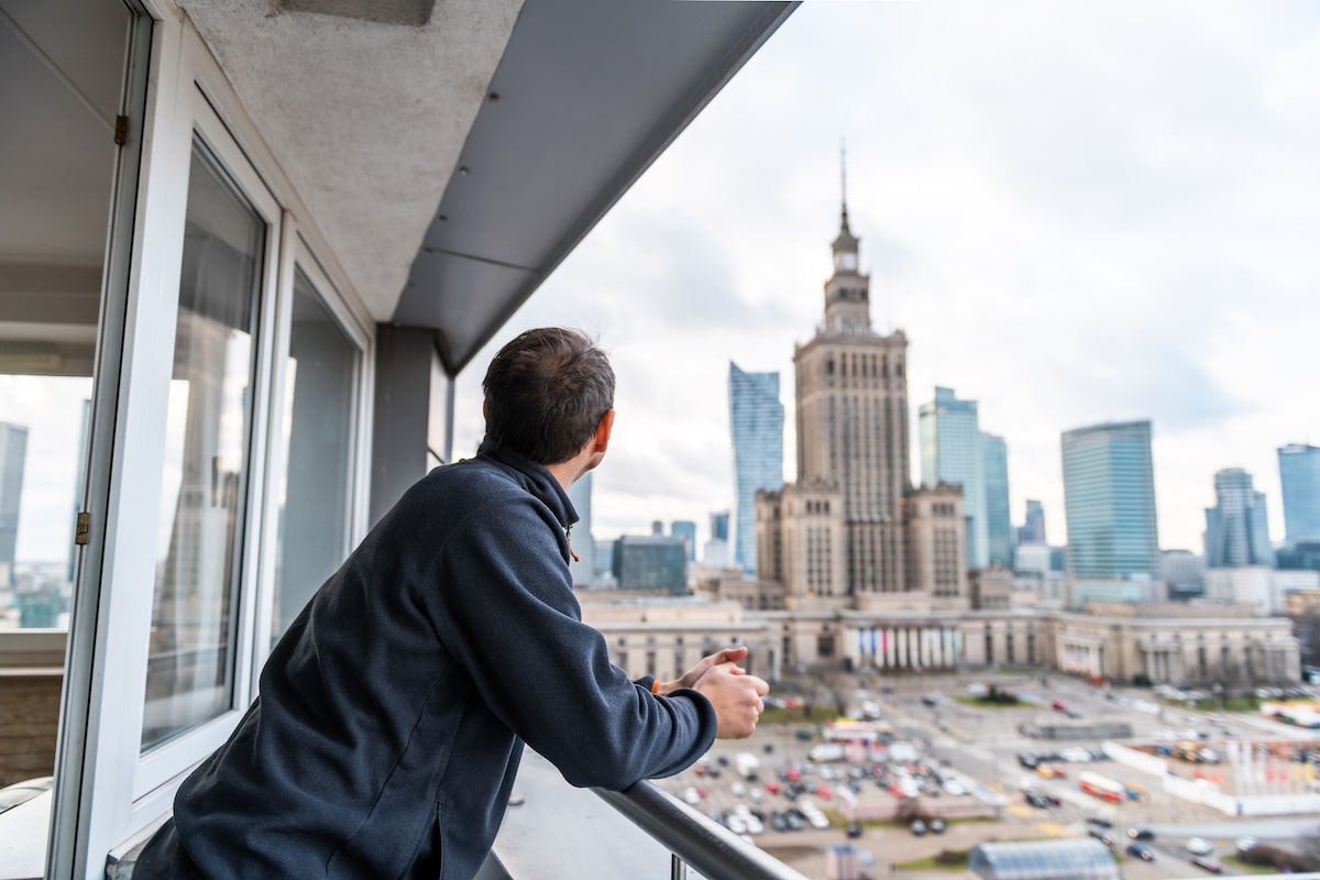Man in apartment looks at city skyline