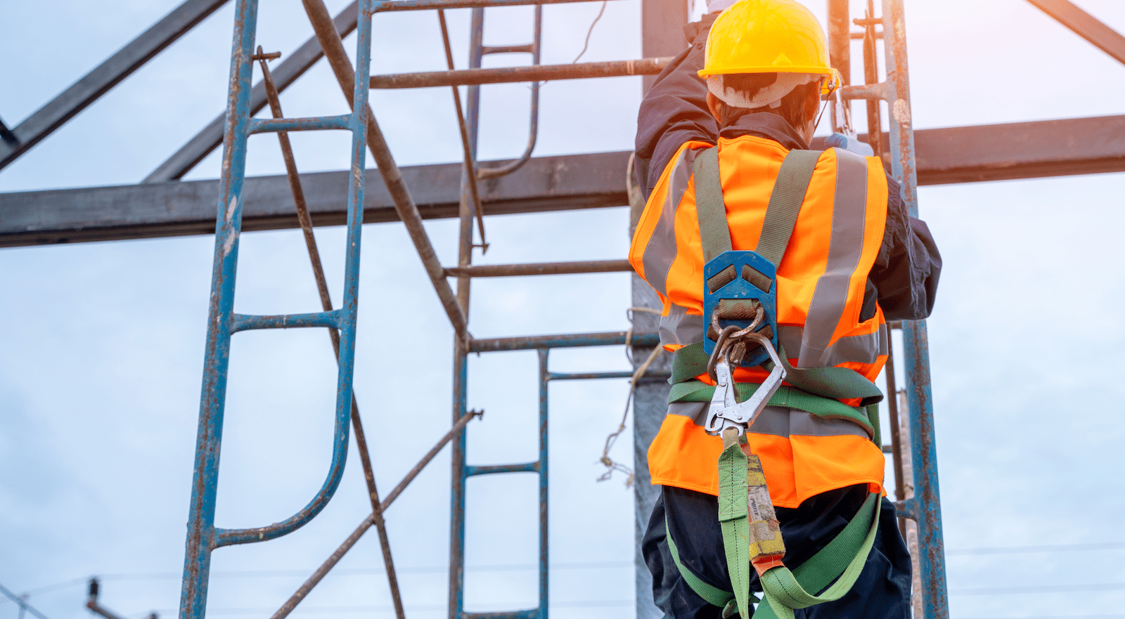 Construction worker wearing safety harness on ladder to comply with OSHA regulations